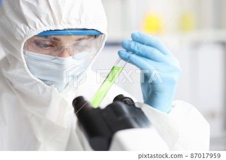 Scientist in protective suit holds test tube with poisonous liquid 87017959
