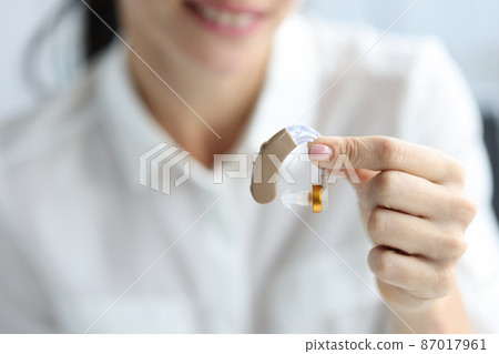 Hearing aid to improve hearing in female hands closeup Hearing aid to improve hearing in female hands closeup 87017961