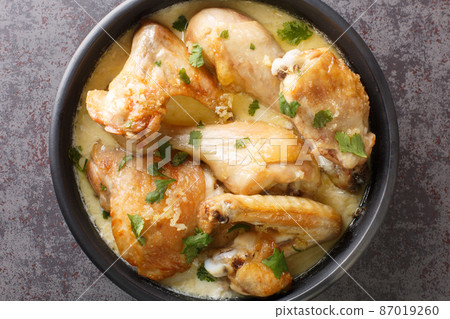 Shkmeruli is a traditional Georgian dish made with fried chicken slowly simmered in a flavorful mixture of milk and garlic closeup in the clay pot. Horizontal top view Shkmeruli is a traditional Georgian dish made with fried chicken slowly simmered in a flavorful mixture of milk and garlic closeup in the clay pot. Horizontal top view 87019260