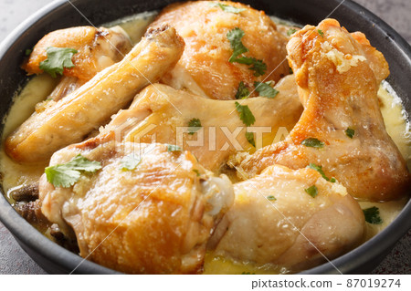 Georgian Chicken Cooked in Milk and Garlic Shkmeruli closeup in the pot. Horizontal 87019274
