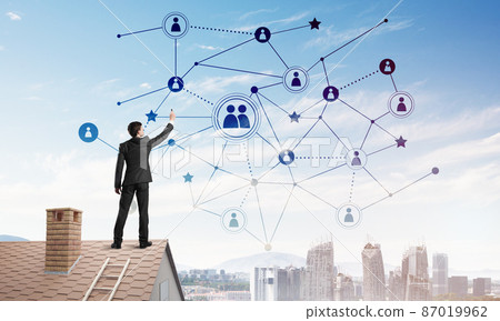 Businessman on house roof presenting networking and connection concept. Mixed media 87019962