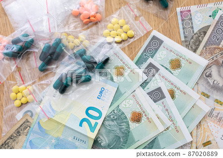 On the table lies currency in banknotes of various countries, and bagged drugs. 87020889