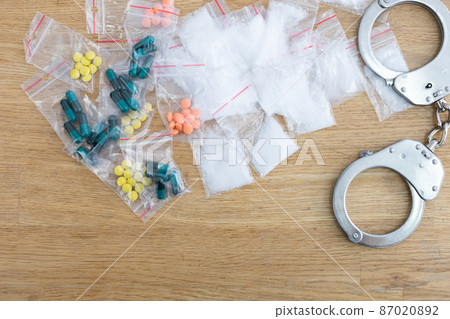 On the table lie bagged loose and toilet drugs and handcuffs. On the table lie bagged loose and toilet drugs and handcuffs. 87020892