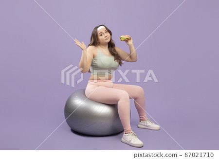 Unsure sad plus size european millennial lady in sportswear doubting whether there burger sitting on fitness ball Unsure sad plus size european millennial lady in sportswear doubting whether there burger sitting on fitness ball 87021710