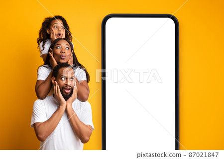 African american family posing near cellphone with blank screen and looking at device with space for your ad, mockup 87021847