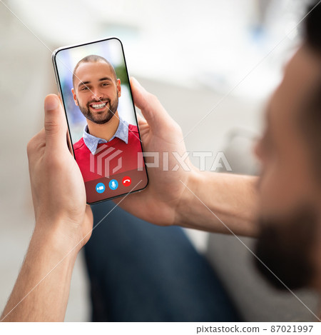 Young man using smartphone for remote meeting with his arab friend 87021997