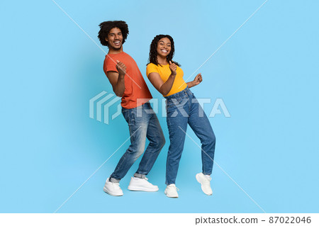 Positive african american couple posing on blue, dancing Positive african american couple posing on blue, dancing 87022046
