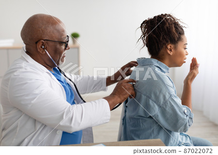 Black male doctor checking breath of female patient Black male doctor checking breath of female patient 87022072