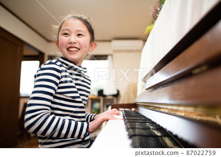 A girl playing the piano A girl playing the piano 87022759