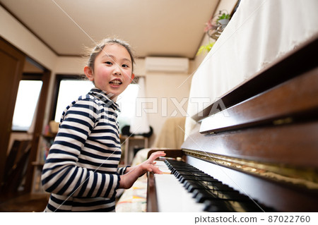 A girl playing the piano A girl playing the piano 87022760
