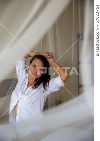 woman waking up stretching arms on the bed in the morning woman waking up stretching arms on the bed in the morning 87023763