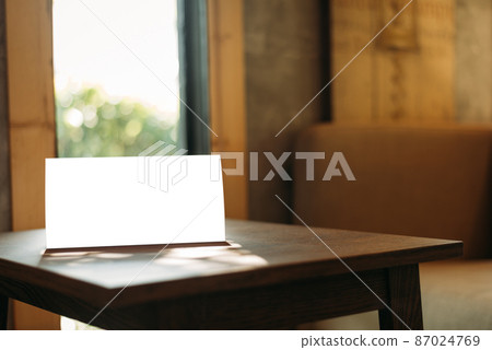 Menu with isolated white on wooden table on blurred restaurant background Menu with isolated white on wooden table on blurred restaurant background 87024769