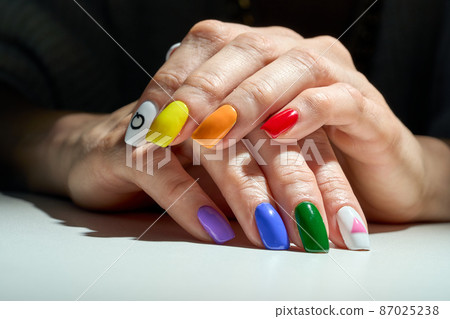 Woman hands with LGBT pride rainbow colours flag manicure. Woman hands with LGBT pride rainbow colours flag manicure. 87025238