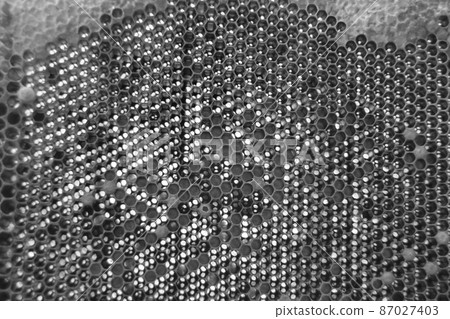 Drop of bee honey drip from hexagonal honeycombs 87027403