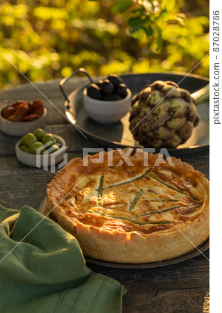 Golden organic healthy crispy pie with artichokes, dried tomatoes and olives on the table 87028786