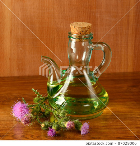 Flowers and oil of thistle on a wooden background. 87029006