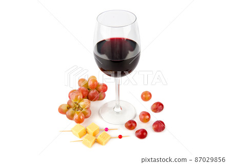 A wineglass of red wine, cheese appetizer and a bunch of grapes isolated on a white. A wineglass of red wine, cheese appetizer and a bunch of grapes isolated on a white. 87029856
