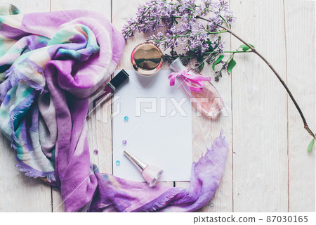 Flat lay, top view spring table desk frame. Feminine desk workspace with cosmetics, lipstick and lilac flowers on wooden background. Flat lay, top view spring table desk frame. Feminine desk workspace with cosmetics, lipstick and lilac flowers on wooden background. 87030165