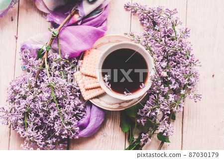 Morning cup of tee, cookies, and lilac flower on wooden table from above. Beautiful breakfast. Flat lay style with copy space Morning cup of tee, cookies, and lilac flower on wooden table from above. Beautiful breakfast. Flat lay style with copy space 87030179