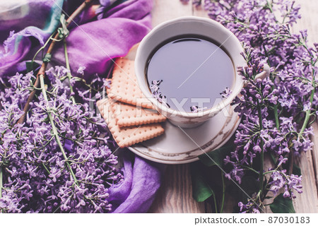 Morning cup of tee, cookies, and lilac flower on wooden table from above. Beautiful breakfast. Flat lay style with copy space Morning cup of tee, cookies, and lilac flower on wooden table from above. Beautiful breakfast. Flat lay style with copy space 87030183
