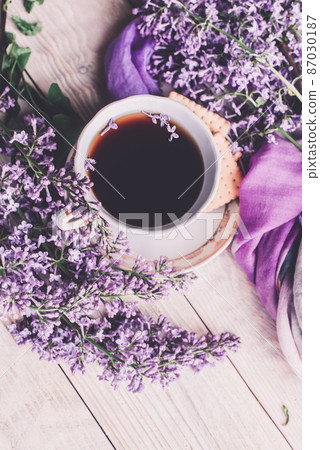 Morning cup of tee, cookies, and lilac flower on wooden table from above. Beautiful breakfast. Flat lay style with copy space Morning cup of tee, cookies, and lilac flower on wooden table from above. Beautiful breakfast. Flat lay style with copy space 87030187