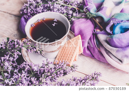 Morning cup of tee, cookies, and lilac flower on wooden table from above. Beautiful breakfast. Flat lay style with copy space 87030189
