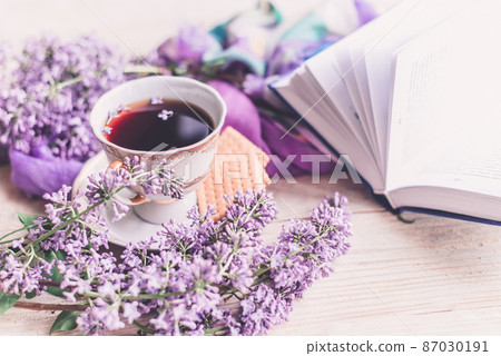Morning cup of tee, cookies, book and lilac flower on wooden table from above. Beautiful breakfast. Flat lay style with copy space Morning cup of tee, cookies, book and lilac flower on wooden table from above. Beautiful breakfast. Flat lay style with copy space 87030191