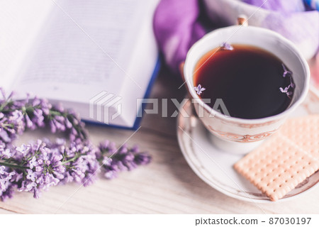 Morning cup of tee, cookies, book and lilac flower on wooden table from above. Beautiful breakfast. Flat lay style with copy space Morning cup of tee, cookies, book and lilac flower on wooden table from above. Beautiful breakfast. Flat lay style with copy space 87030197