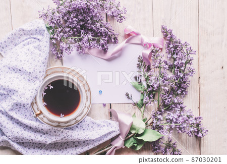 Morning cup of tee, cookies, and lilac flower on wooden table from above. Beautiful breakfast. Flat lay style with copy space Morning cup of tee, cookies, and lilac flower on wooden table from above. Beautiful breakfast. Flat lay style with copy space 87030201