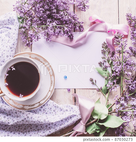 Morning cup of tee, cookies, and lilac flower on wooden table from above. Beautiful breakfast. Flat lay style with copy space Morning cup of tee, cookies, and lilac flower on wooden table from above. Beautiful breakfast. Flat lay style with copy space 87030273