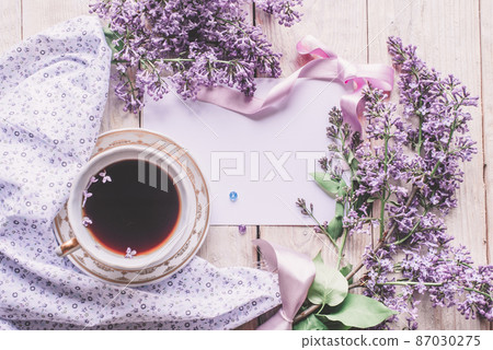 Morning cup of tee, cookies, and lilac flower on wooden table from above. Beautiful breakfast. Flat lay style with copy space Morning cup of tee, cookies, and lilac flower on wooden table from above. Beautiful breakfast. Flat lay style with copy space 87030275