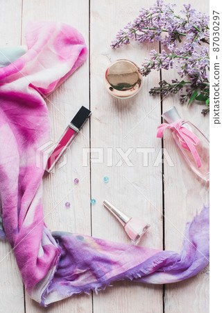Flat lay, top view spring table desk frame. Feminine desk workspace with cosmetics, lipstick and lilac flowers on wooden background. Flat lay, top view spring table desk frame. Feminine desk workspace with cosmetics, lipstick and lilac flowers on wooden background. 87030297