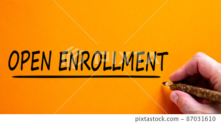 Hand writing 'open enrollment', isolated on beautiful orange background. Concept. Copy space. 87031610