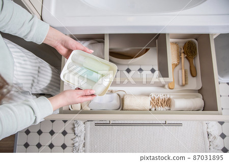 Housewife hands putting rolled up towel into drawer under sink. Organizing storage space in bathroom 87031895