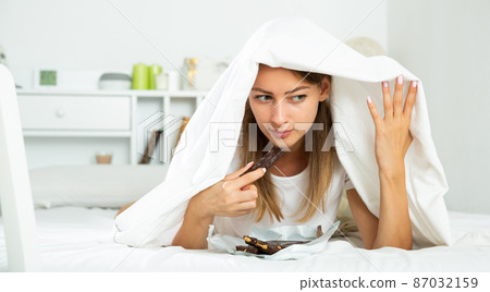 Woman eating chocolate in bed 87032159