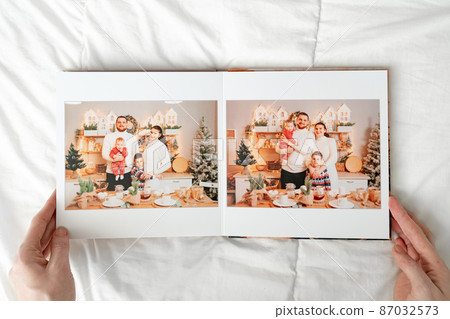 a hands with a book with photos of big family on a white background. a hands with a book with photos of big family on a white background. 87032573