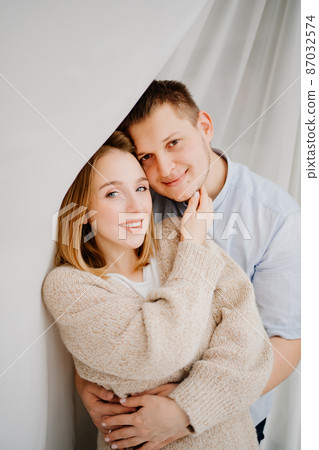 a happy and loving couple hugs against the background of a white curtain. a happy and loving couple hugs against the background of a white curtain. 87032574