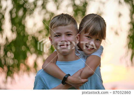 Happy siblings hugging lovingly in summer park. Young children brother and sister embracing each other outdoors. Family love and relationship concept Happy siblings hugging lovingly in summer park. Young children brother and sister embracing each other outdoors. Family love and relationship concept 87032860