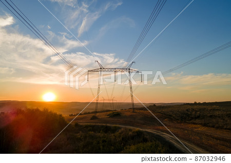 Dark silhouette of high voltage tower with electric power lines at sunrise. Transmission of electric energy concept 87032946