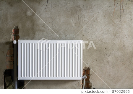 Close-up view of new isolated installed heating radiator on brick rough plastered wall in an empty room of a newly built apartment or house. Construction, maintenance, plumbing and repairing concept. Close-up view of new isolated installed heating radiator on brick rough plastered wall in an empty room of a newly built apartment or house. Construction, maintenance, plumbing and repairing concept. 87032965