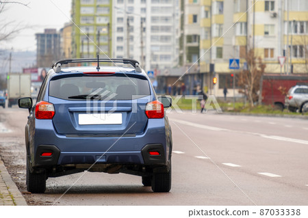Cars parked in a row on a city street side. 87033338