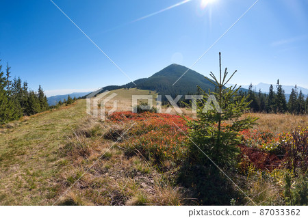 Bright landscape with grassy green meadow and distant mountain hills in summer Bright landscape with grassy green meadow and distant mountain hills in summer 87033362