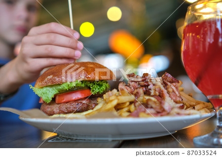 Closeup of tasty burger and french fries with meat on plate in restaurant. 87033524