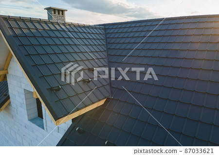 Aerial view of unfinished house with aerated lightweight concrete walls and wooden roof frame covered with metallic tiles under construction. Aerial view of unfinished house with aerated lightweight concrete walls and wooden roof frame covered with metallic tiles under construction. 87033621