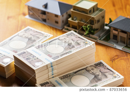A bundle of bills (money) and a model house 87033656