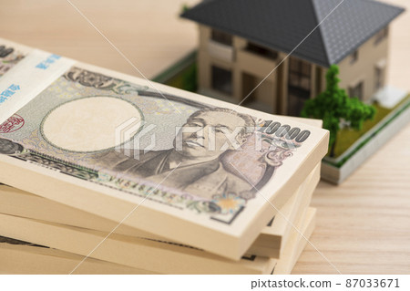 A bundle of bills (money) and a model house A bundle of bills (money) and a model house 87033671