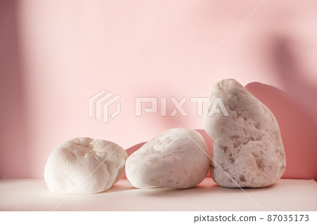 White stones on pink pastel background. Abstract background, mock up minimal scene geometry shape podium for cosmetic product display. Stage pedestal or platform White stones on pink pastel background. Abstract background, mock up minimal scene geometry shape podium for cosmetic product display. Stage pedestal or platform 87035173