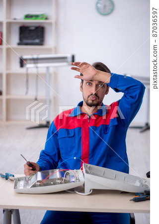 Young male repairman repairing heater Young male repairman repairing heater 87036597