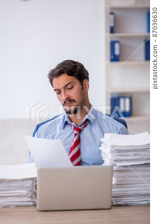 Young male employee and too much work in the office Young male employee and too much work in the office 87036630
