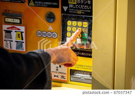 Female who pushes the checkout button of coin parking Coin parking 87037347